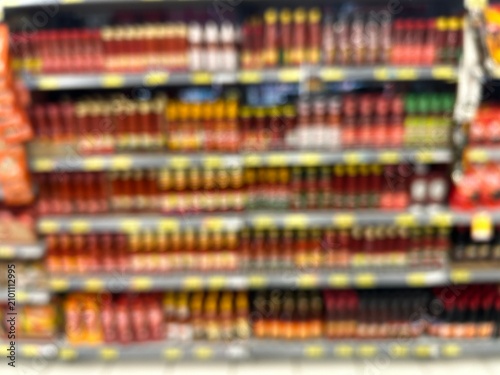 Blurred background of supermarket shelf display with bottled sauces, condiments, and chili sauce