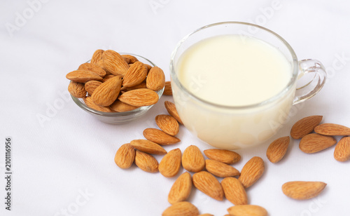 Fotografie Almond milk in a glass cup with almond nuts on a white background