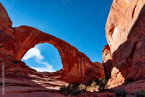 Natural sandstone arch formation under clear blue sky in a desert landscape