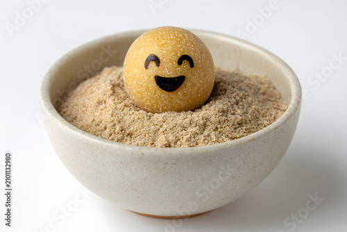 Cute yellow emoji ball in a small ceramic bowl of sand