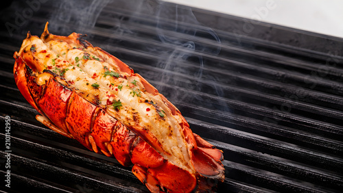 Grilled lobster tail seasoned with herbs on a hot barbecue
