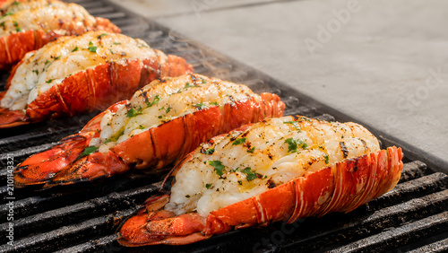 Fresh seasoned lobster tails cooking on a hot charcoal grill