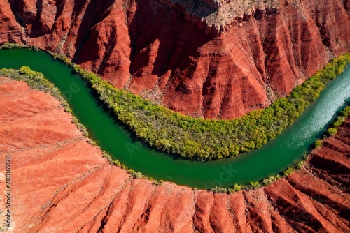 Aerial view of a winding green river cutting through red rock canyon landscape