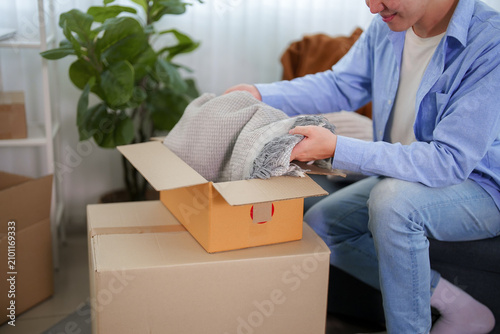 Canvastavla Asian man unpacking bubble wrap from cardboard box while relocating to new apart