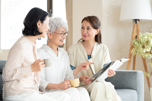 ソファで本を見る中高年の女性たち3人