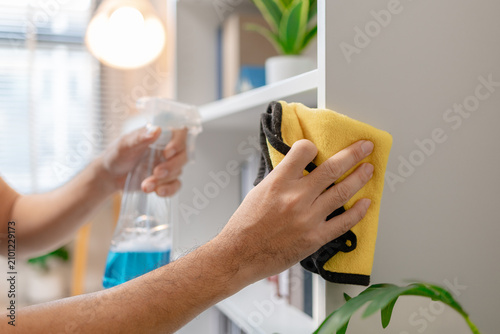 Professional home and office cleaning with disinfecting spray, wiping shelves, dusting furniture and sanitizing sofa surfaces to maintain a clean, organized and healthy indoor environment.