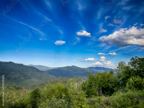 Sunny Carpathian peaks: green valleys and cloudy skies.