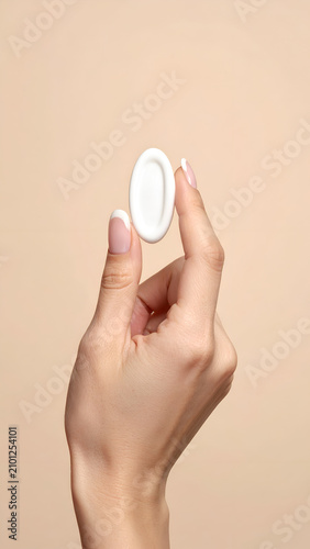 Close up of a womans hand holding a white diaphragm for birth control.