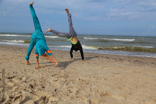 Couple legs up balance poses beach, man woman acrobatic flexibility poses