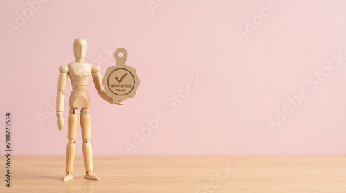 Mid-year performance reviews and employee evaluation approval concept with wooden mannequin holding checked quality stamp badge with copy space for business growth presentation banner