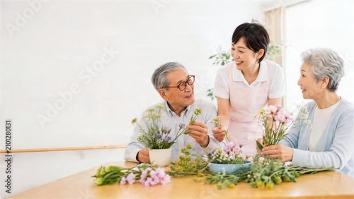 介護施設で高齢者と花を生ける女性スタッフ