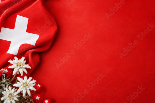 Swiss themed background featuring edelweiss blossoms and flag, Swiss National Day or travel.