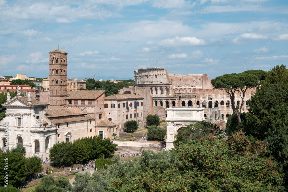 Obraz premium Scenic panoramic view of the historic Roman Forum showing the Basilica of Santa Francesca Romana, the Arch of Titus, and the Colosseum in Rome, Italy