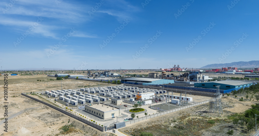 Obraz premium Aerial View of a Grid-Connected Battery Energy Storage Power Station Adjacent to Industrial Complex in Arid Region