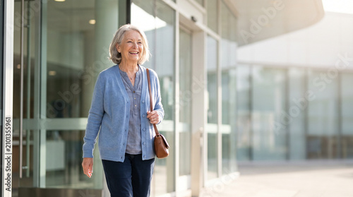 Senior woman leaving hospital after successful rehabilitation recovery