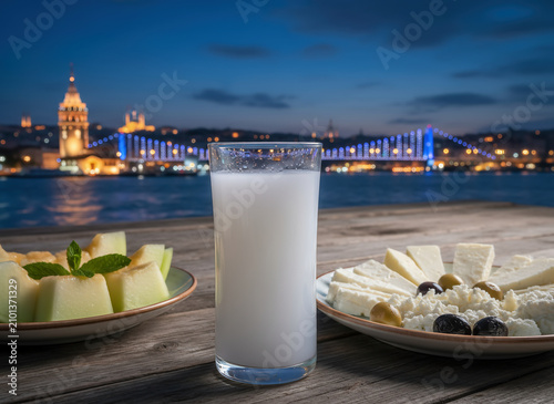 Traditional Turkish rakı served with assorted meze and white cheese by the Bosphorus at night, celebrating authentic Turkish dining culture and social gatherings.