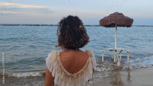 girl looks at the sea at sunset