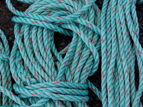 Turquoise fishing ropes have been coiled and stored creating an abstract pattern and image