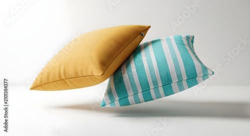 Two decorative throw pillows, one mustard yellow and one turquoise with white stripes, floating against a white background.