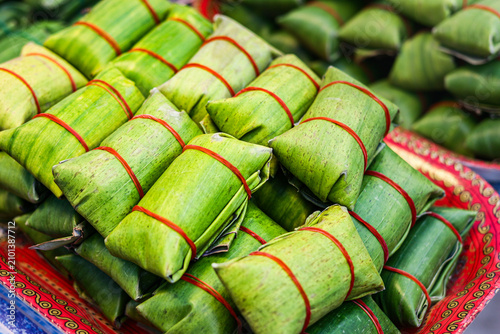 Bild auf Leinwand Pile of authentic steamed pork sausage wrapped in fresh green banana leaves