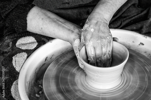 potter models the clay on a potter's wheel