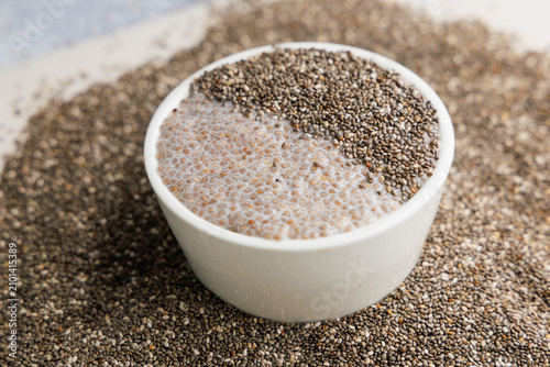 Foto Chia seeds in a bowl surrounded by loose seeds with water, chia pudding soaking
