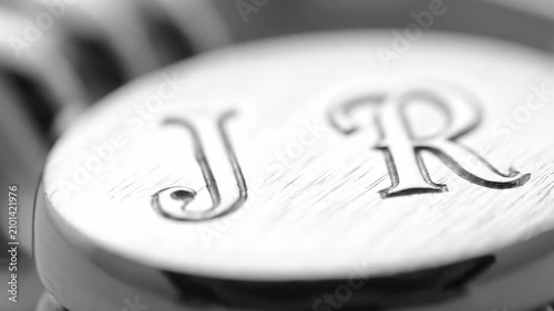 Close-up of elegant engraved initials JR on a shiny metallic surface