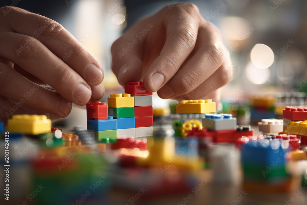 Fototapeta premium Fingers skillfully connecting colorful LEGO bricks in a cozy indoor space during a creative building session