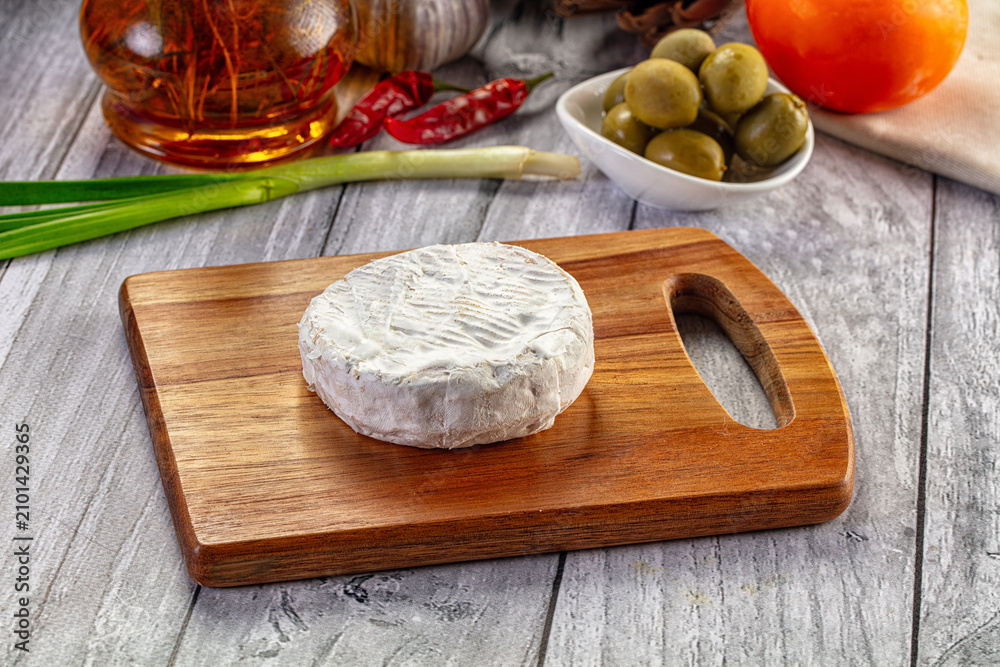 Fototapeta premium Round Camembert Cheese on Wooden Board with Olives and Spices