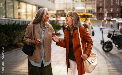Fotografie Two mature women, dressed in a tan blazer and an orange leather coat, face each