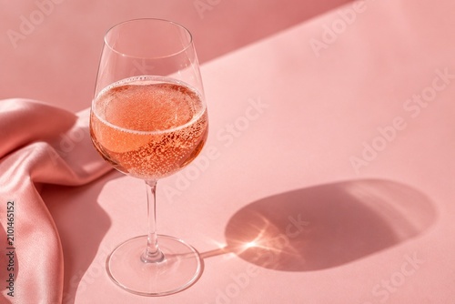 A delicate glass of rosé wine placed on a soft pink surface, radiating elegance and subtle charm.