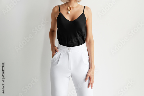 Φωτογραφία Minimalist outfit featuring a black silk camisole and white high waisted trousers