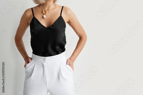 Принти на полотні Woman in a black silk camisole and white high-waisted trousers, hands in pockets