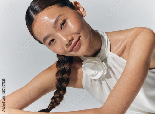 A beautiful young Asian woman with a braided hairstyle smiling in a studio