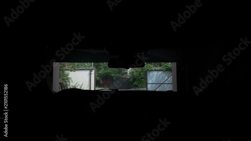 View from inside car exiting home garage into sunny suburban street in summer