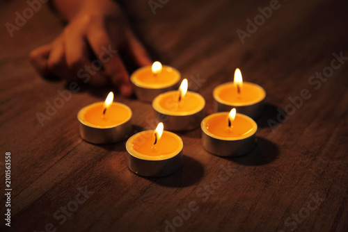 Photos Hands arranging lit tealight candles on a wooden table creating a warm and peace