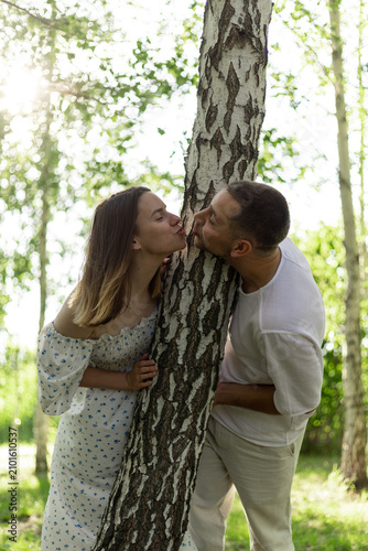 Obraz na plátně Romantic couple playfully interacting with a tree in a sunny forest setting