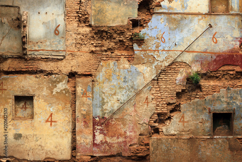 Photos Weathered wall of a dilapidated historic building with peeling paint, exposed br