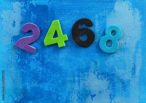 Bild auf Leinwand Colorful numbers 2, 4, 6 and 8 arranged on blue acrylic canvas background, representing even numbers, early math learning, preschool education, numeracy, counting practice, classroom activities