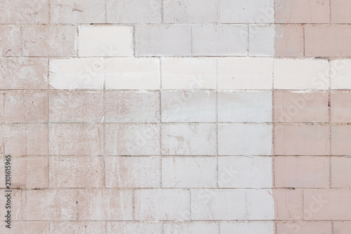 Photos Faded pink and white painted cinderblock wall with visible texture, weathering and a horizontal white stripe