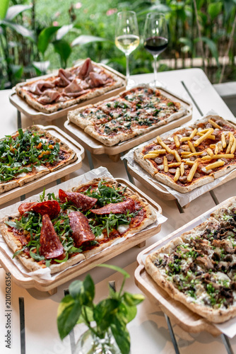 many different Pinsa types on garden restaurant pizza slice buffet table outdoors