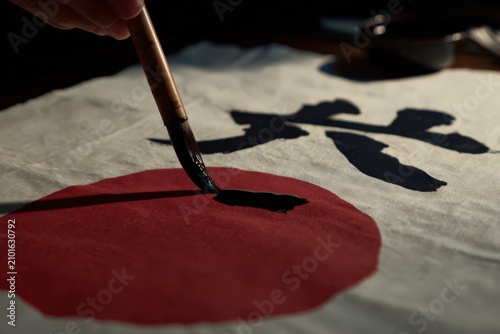 Calligraphy artist practices kanji painting with a brush on fabric in Japan during evening hours