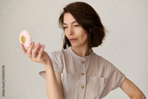 Quadro su tela Elegant woman admires her reflection while showcasing flawless style in soft lig