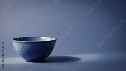A serene blue ceramic bowl on a matching blue background with soft lighting and subtle shadows