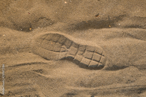 фотографія Close-up of a boot footprint impressed in textured brown beach sand
