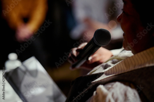 Фотография Close up of middle aged woman speaking into microphone during public event, addressing audience and sharing message