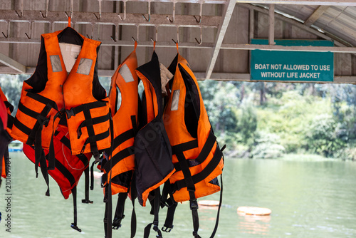 Canvastavla Orange life jackets hanging at a boat dock with a safety sign in the background