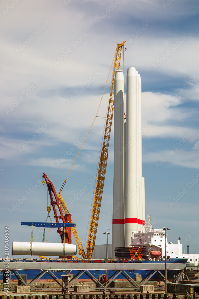 Fototapeta premium Giant Crawler Crane Assembling Wind Turbine Tower Sections at Port Harbor, Sustainable Offshore Renewable Energy Construction and Logistics