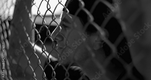Obraz na płótnie Hispanic man behind fence lost in ruminating thoughts, reflecting on past mistak