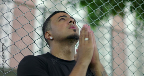 фотографія Hispanic Latino man of African descent looking upward with hands clasped in pray